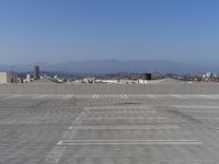 a parking lot with mountains in the background and blue sky overhead, viewed from above