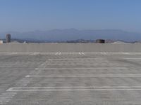 a parking lot with mountains in the background and blue sky overhead, viewed from above