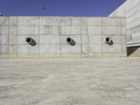 the side of an empty concrete structure with four cement round holes on each side of it