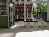 a white tiled floor near glass doors and windows with people sitting on the sidewalk in front