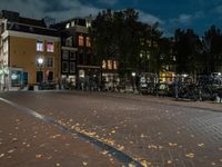 bicycles and lights illuminate the walkway in an otherwise empty city block near many parked buildings