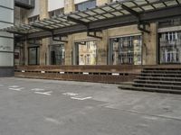 an empty building with signs on the street and people on bikes in traffic passing by