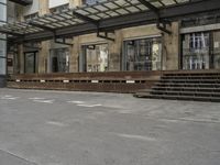 an empty building with signs on the street and people on bikes in traffic passing by