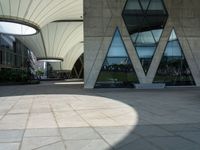 a square paved area has three arches and is set high on one of several tall buildings