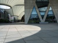 a square paved area has three arches and is set high on one of several tall buildings