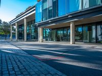 there is a man walking along the street on his bike in front of the building