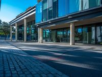 there is a man walking along the street on his bike in front of the building