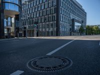 empty road surrounded by a glass office building on a sunny day with blue skies in the background