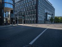 empty road surrounded by a glass office building on a sunny day with blue skies in the background