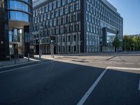 empty road surrounded by a glass office building on a sunny day with blue skies in the background