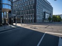 empty road surrounded by a glass office building on a sunny day with blue skies in the background