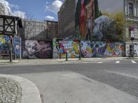 the street in front of the graffiti covered building is empty and empty, but has two rows