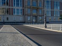 a street light next to an empty road in front of a building with a traffic light on top of it