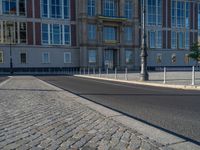 a street light next to an empty road in front of a building with a traffic light on top of it