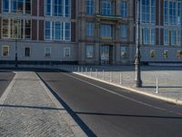 a street light next to an empty road in front of a building with a traffic light on top of it