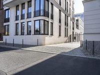 a person with a motorcycle is parked next to a tall building on a city street