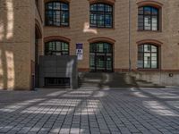 a brick courtyard has steps leading up to it, and a blue umbrella is on the ground