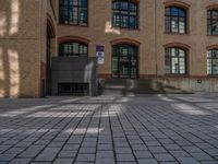 a brick courtyard has steps leading up to it, and a blue umbrella is on the ground