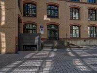 a brick courtyard has steps leading up to it, and a blue umbrella is on the ground