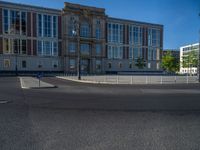 a street light next to an empty road in front of a building with a traffic light on top of it