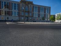 a street light next to an empty road in front of a building with a traffic light on top of it