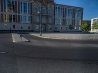 a street light next to an empty road in front of a building with a traffic light on top of it