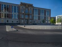 a street light next to an empty road in front of a building with a traffic light on top of it