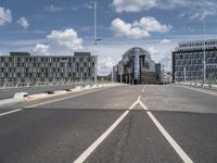 empty street on a sunny day with buildings in the background and the sky full of clouds