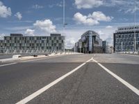 empty street on a sunny day with buildings in the background and the sky full of clouds