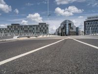 empty street on a sunny day with buildings in the background and the sky full of clouds