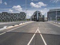 empty street on a sunny day with buildings in the background and the sky full of clouds