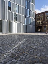 some people walking on a brick floor in front of a building on a city street