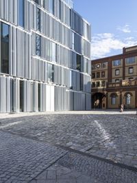 some people walking on a brick floor in front of a building on a city street