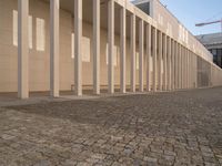 a room with columns near a building with light pouring through it and shadows in the windows