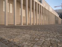 a room with columns near a building with light pouring through it and shadows in the windows