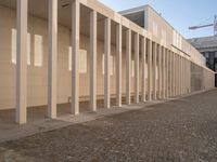 a room with columns near a building with light pouring through it and shadows in the windows