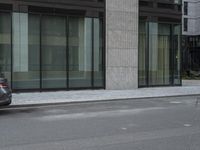 a man riding a motorcycle down a road past tall buildings and cars parked near by