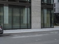 a man riding a motorcycle down a road past tall buildings and cars parked near by