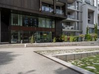 a woman with her bike is walking on the sidewalk by a building or condo complex