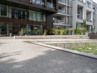 a woman with her bike is walking on the sidewalk by a building or condo complex