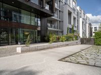 a woman with her bike is walking on the sidewalk by a building or condo complex