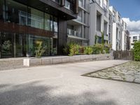 a woman with her bike is walking on the sidewalk by a building or condo complex