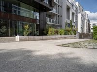 a woman with her bike is walking on the sidewalk by a building or condo complex