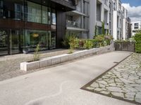 a woman with her bike is walking on the sidewalk by a building or condo complex