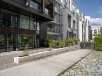 a woman with her bike is walking on the sidewalk by a building or condo complex