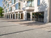 a brick sidewalk outside of a building with glass windows on either side and the street in front of it