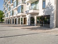 a brick sidewalk outside of a building with glass windows on either side and the street in front of it