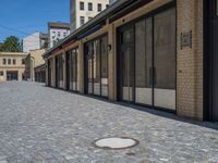 the sidewalk is paved with stones and has a bench in front of it, with no people inside