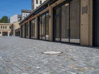 the sidewalk is paved with stones and has a bench in front of it, with no people inside