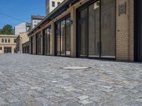 the sidewalk is paved with stones and has a bench in front of it, with no people inside